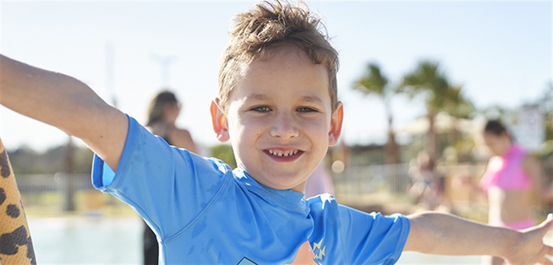 A boy smiling at the camera while playing at the Billabong