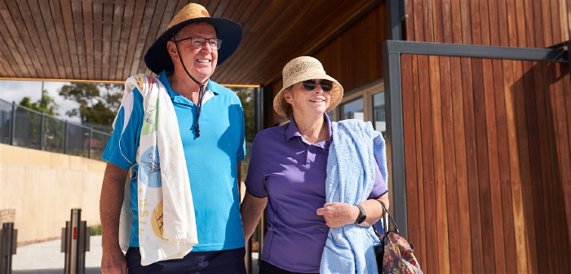 A couple smiling, standing in front of the Billabong Parklands entrance