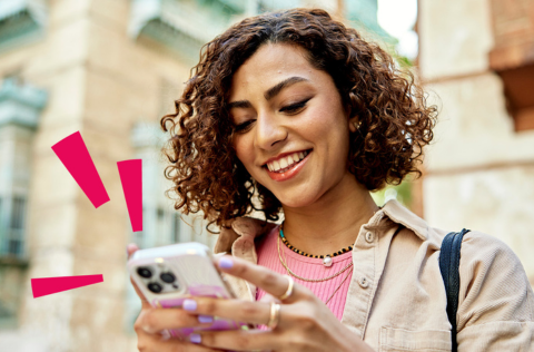 Woman with curly hair smiling looking at her phone