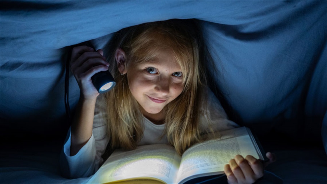 Young girl reading by torchlight