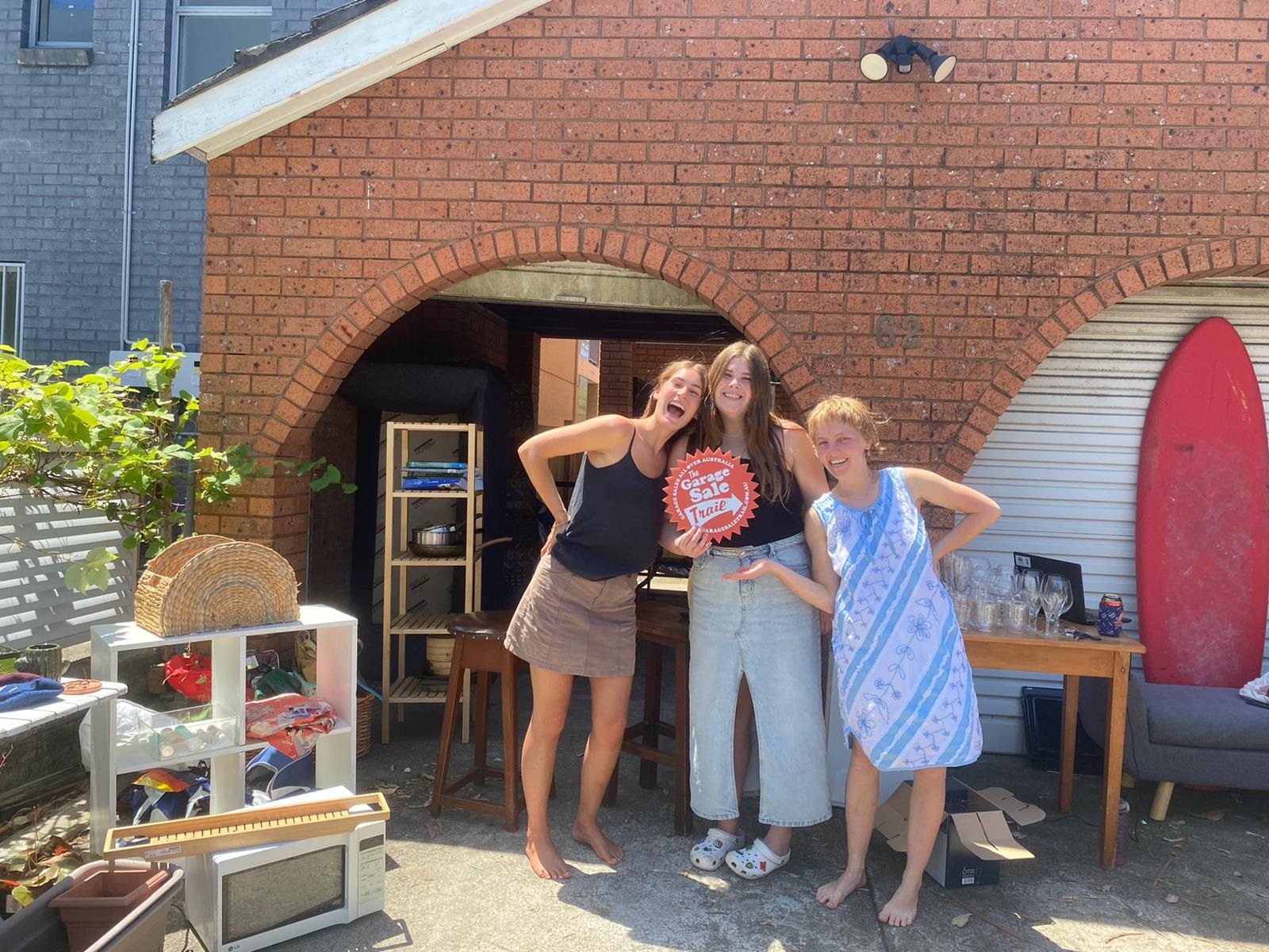 Three women pose with garage sale items