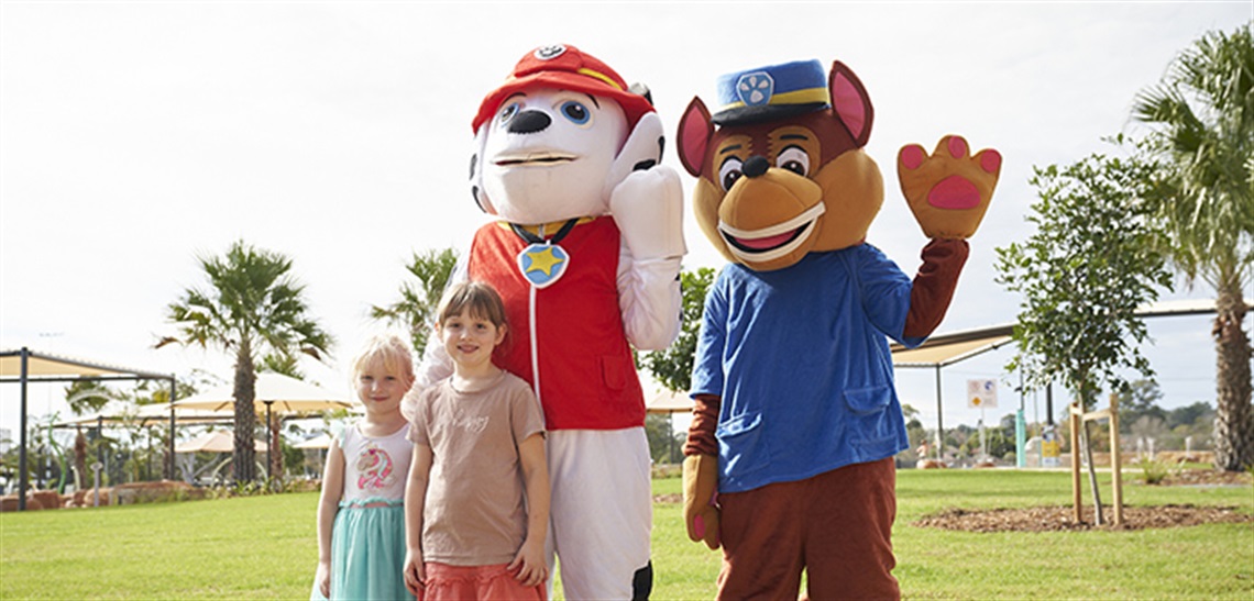 Two children stand with characters from Paw Patrol at the Billabong