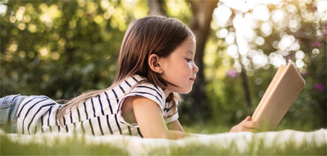 Child relaxing and reading at park